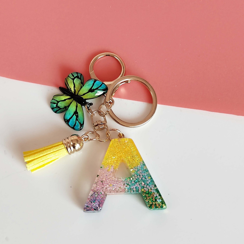 Ristäärisega 26 initsiaali vikerkaare järkjärgulise tutiga liblika ripatsiga võtmehoidja, litritega liimvaigust võtmehoidja