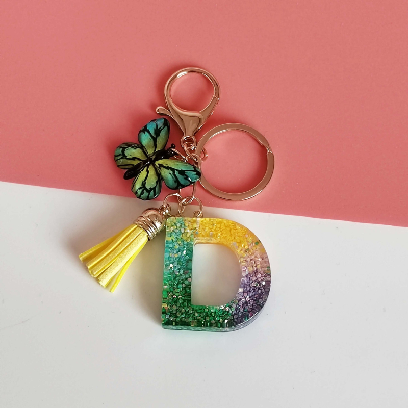 Ristäärisega 26 initsiaali vikerkaare järkjärgulise tutiga liblika ripatsiga võtmehoidja, litritega liimvaigust võtmehoidja