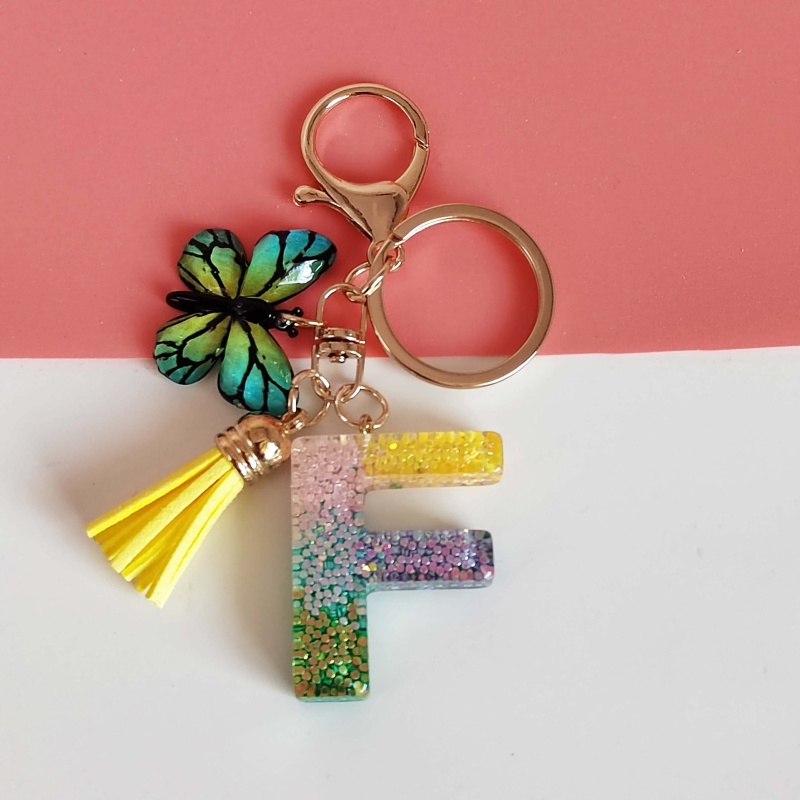 Ristäärisega 26 initsiaali vikerkaare järkjärgulise tutiga liblika ripatsiga võtmehoidja, litritega liimvaigust võtmehoidja