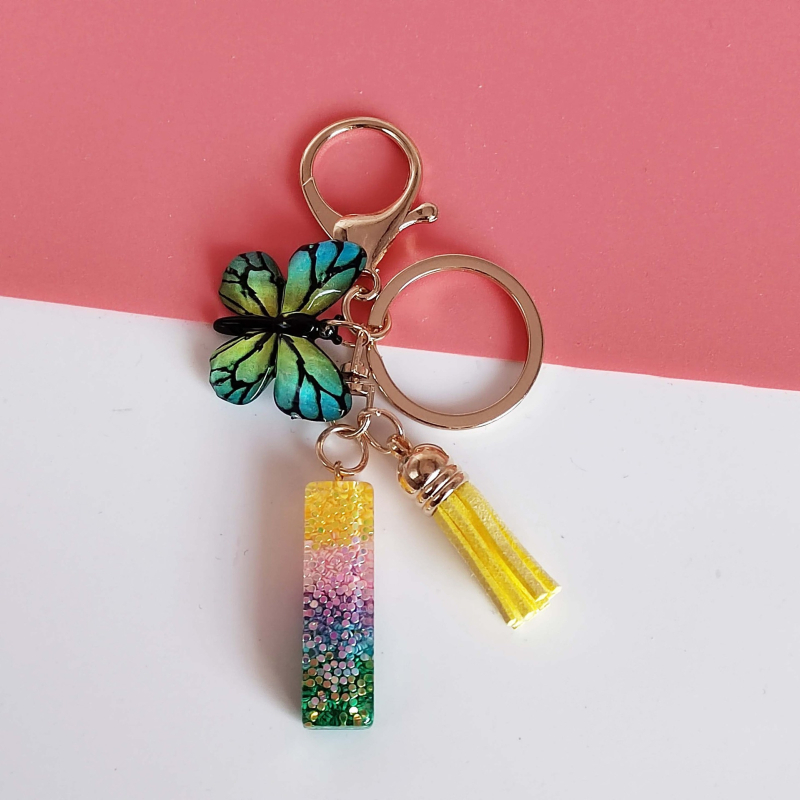 Ristäärisega 26 initsiaali vikerkaare järkjärgulise tutiga liblika ripatsiga võtmehoidja, litritega liimvaigust võtmehoidja