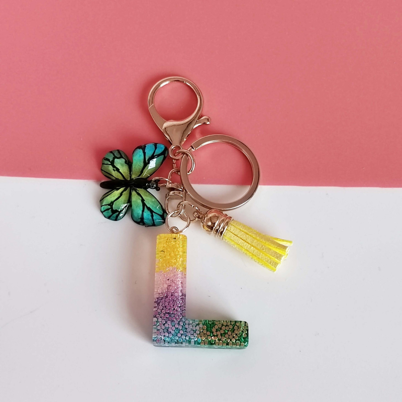 Ristäärisega 26 initsiaali vikerkaare järkjärgulise tutiga liblika ripatsiga võtmehoidja, litritega liimvaigust võtmehoidja