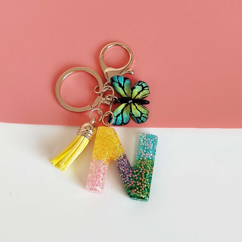 Ristäärisega 26 initsiaali vikerkaare järkjärgulise tutiga liblika ripatsiga võtmehoidja, litritega liimvaigust võtmehoidja