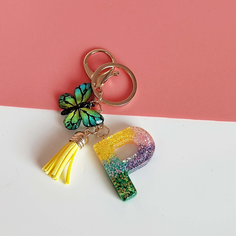 Ristäärisega 26 initsiaali vikerkaare järkjärgulise tutiga liblika ripatsiga võtmehoidja, litritega liimvaigust võtmehoidja