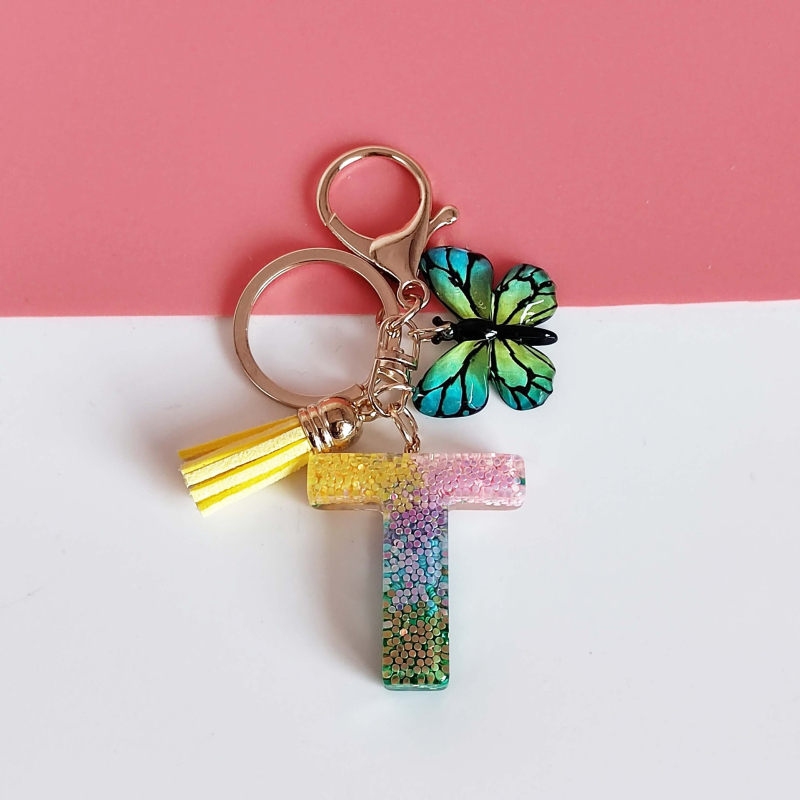 Ristäärisega 26 initsiaali vikerkaare järkjärgulise tutiga liblika ripatsiga võtmehoidja, litritega liimvaigust võtmehoidja