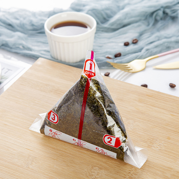 Dvisluoksnis trikampis ryžių kamuoliukų pakavimo maišelis, pusiau supjaustyti jūros dumbliai, rankomis susukta suši pakuotė, lengvai plyštanti ir nerasojanti, japoniško stiliaus jūros dumbliais apvyniota akmens masė