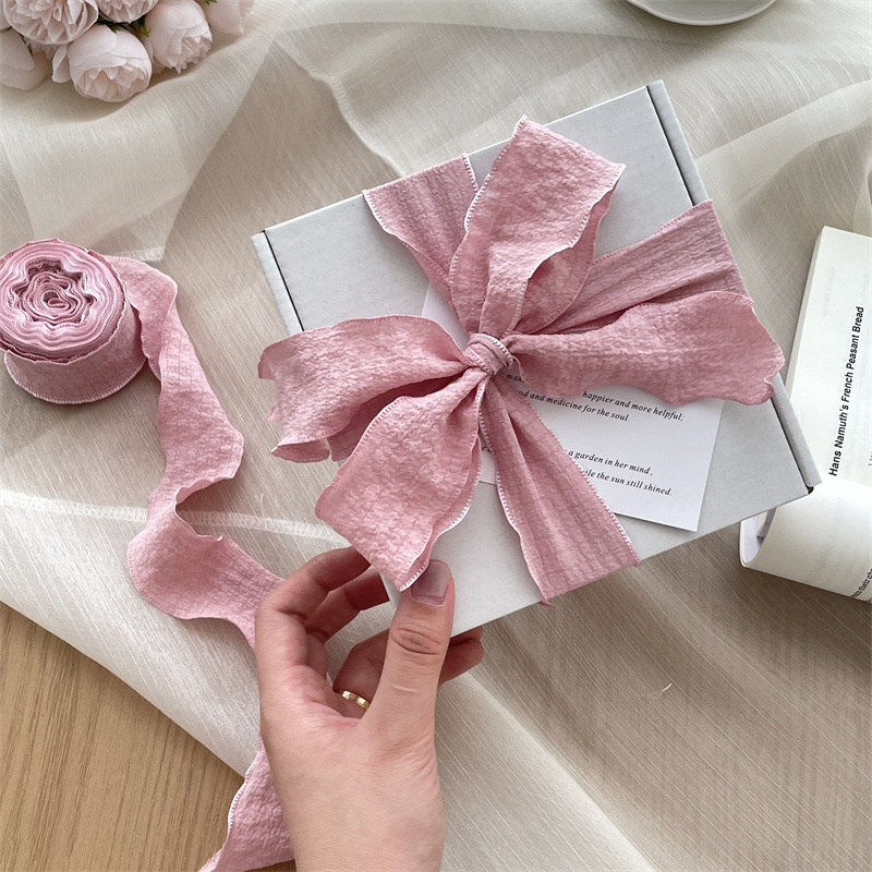 Vėjo klostuota audinio juostelė, didelis pakavimo juostelės ritinėlis, graži minkšta peteliškė, gėlių kaklaraištis