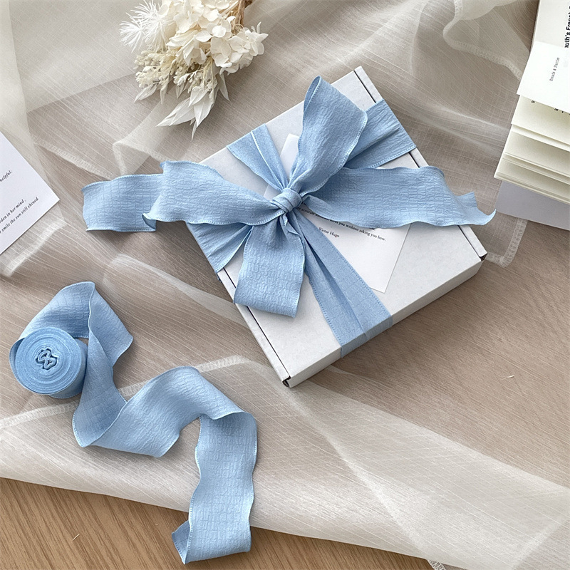 Vėjo klostuota audinio juostelė, didelis pakavimo juostelės ritinėlis, graži minkšta peteliškė, gėlių kaklaraištis