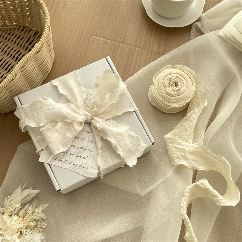 Vėjo klostuota audinio juostelė, didelis pakavimo juostelės ritinėlis, graži minkšta peteliškė, gėlių kaklaraištis