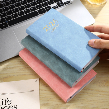 Laos olev 2026. aasta A6 formaadis ingliskeelne planeerija värvilise kuuindeksiga, paksendatud kalendriga, piiriülese teemapäevikuga