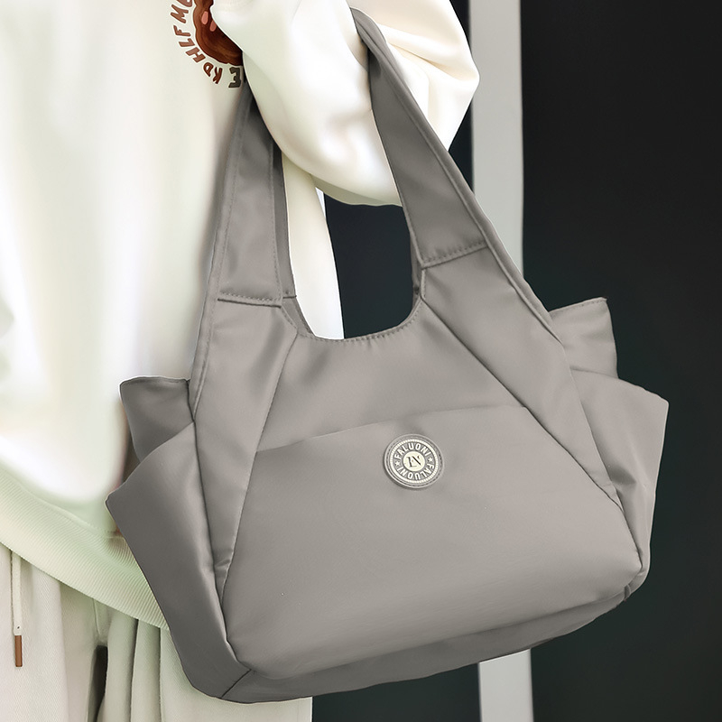 Nylonová tote taška, horizontálny štvorcový tvar, zapínanie na zips, vnútorné vrecká (zipsové vrecko, vrecko na telefón, vrecko na ID), dvojité popruhy