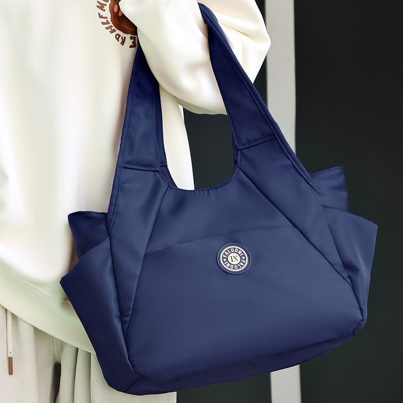 Nylonová tote taška, horizontálny štvorcový tvar, zapínanie na zips, vnútorné vrecká (zipsové vrecko, vrecko na telefón, vrecko na ID), dvojité popruhy