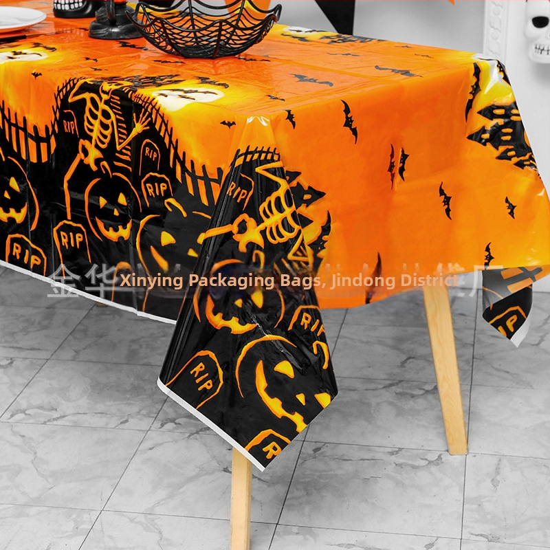 Jednorázový plastový obrus na Halloween párty s motívmi tekvice, lebky a netopiera v štýle karikatúrneho hororu.