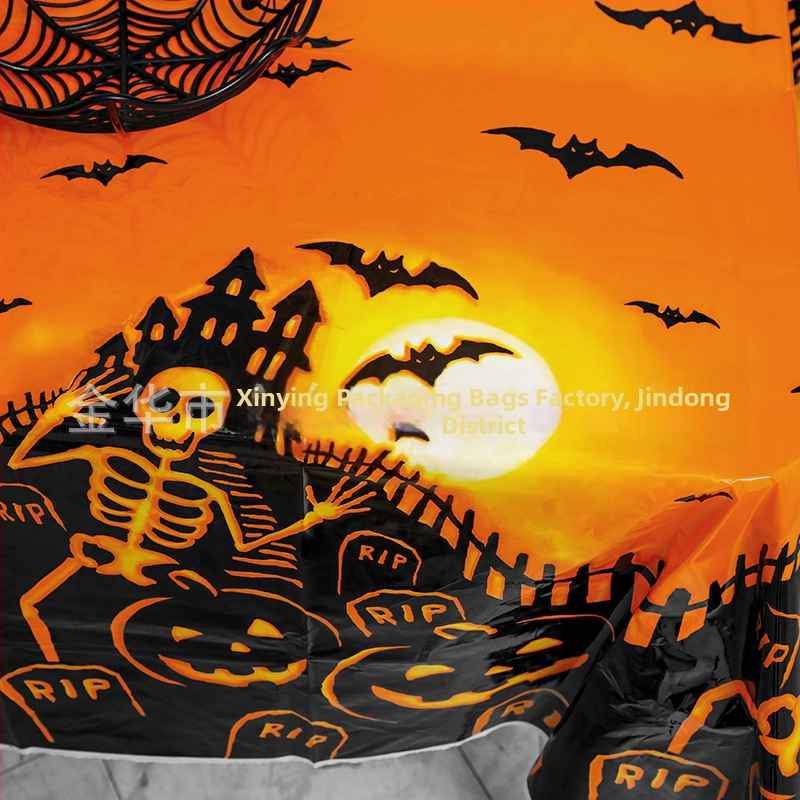 Jednorázový plastový obrus na Halloween párty s motívmi tekvice, lebky a netopiera v štýle karikatúrneho hororu.