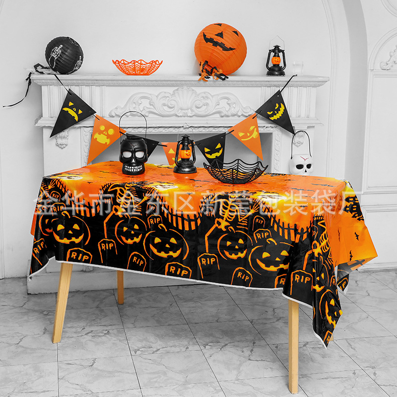 Jednorázový plastový obrus na Halloween párty s motívmi tekvice, lebky a netopiera v štýle karikatúrneho hororu.