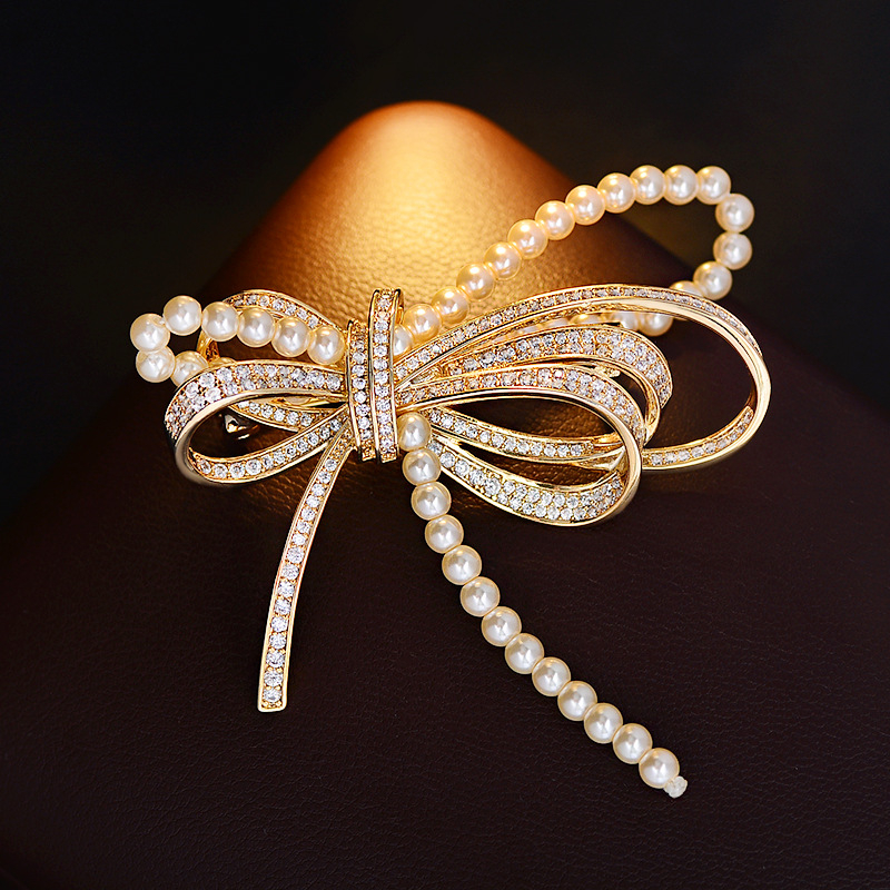 Rézből készült masni alakú brooch mikro-beültetett cirkóniával és gyöngyökkel, elegáns könnyed luxus, 2025 nyár