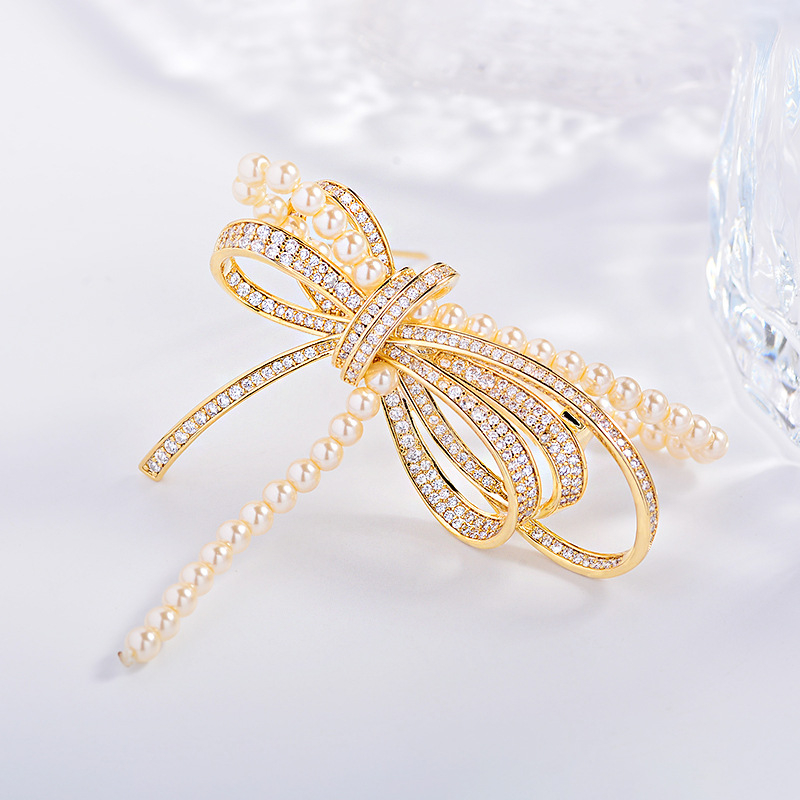 Rézből készült masni alakú brooch mikro-beültetett cirkóniával és gyöngyökkel, elegáns könnyed luxus, 2025 nyár