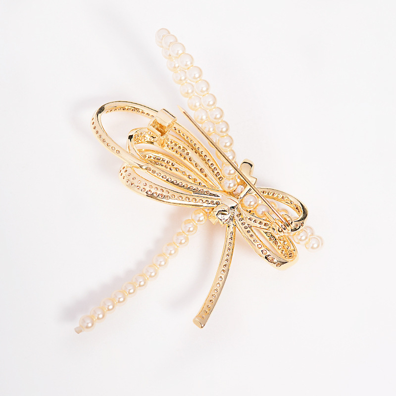 Rézből készült masni alakú brooch mikro-beültetett cirkóniával és gyöngyökkel, elegáns könnyed luxus, 2025 nyár