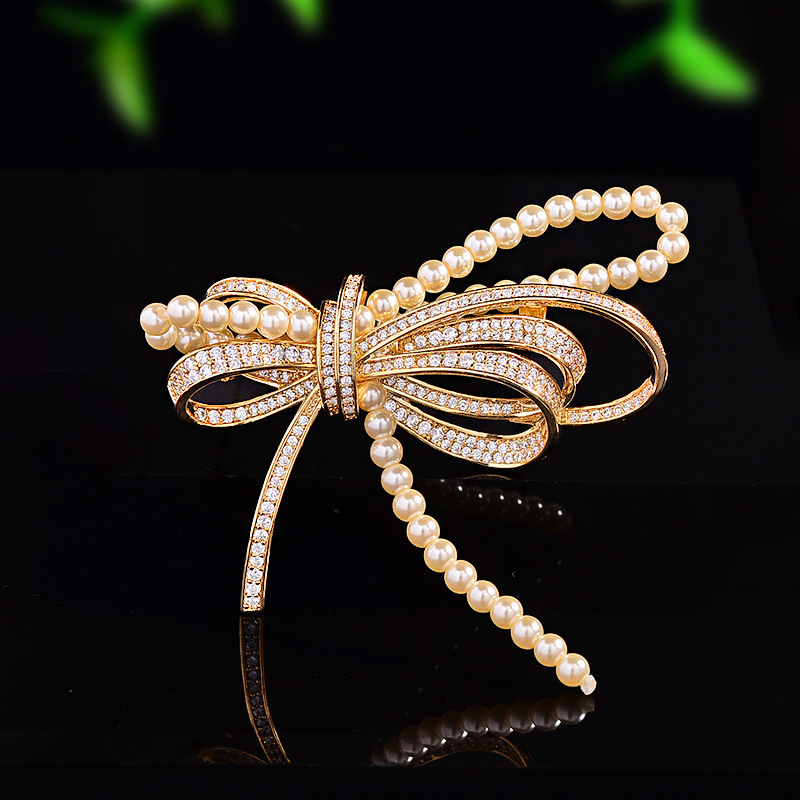 Rézből készült masni alakú brooch mikro-beültetett cirkóniával és gyöngyökkel, elegáns könnyed luxus, 2025 nyár