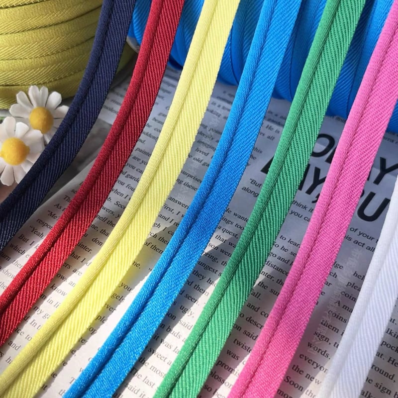Elastīga vienpusēja malu lente apģērbam un mājas tekstilizstrādājumiem; piemērota šūšanai apģērbam, skolas uniformes biksēm, spilveniem un aizkariem