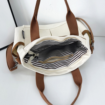 Geantă tote din pânză, cu stil urban minimalist, formă orizontală pătrată, închidere cu fermoar, buzunar pentru ID, trei curele de umăr și căptușeală poliester-bumbac.