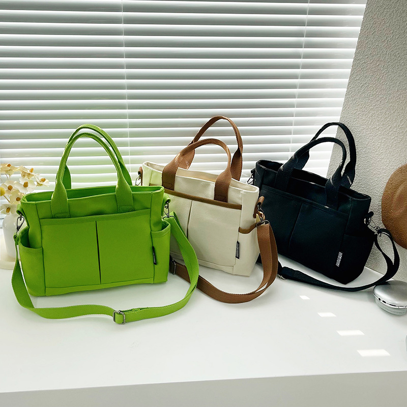 Geantă tote din pânză, cu stil urban minimalist, formă orizontală pătrată, închidere cu fermoar, buzunar pentru ID, trei curele de umăr și căptușeală poliester-bumbac.