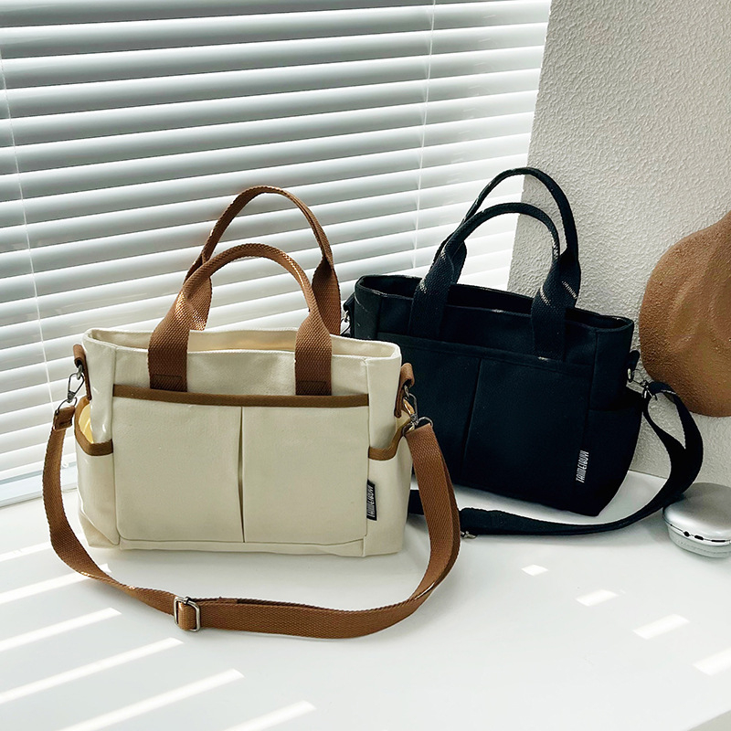 Geantă tote din pânză, cu stil urban minimalist, formă orizontală pătrată, închidere cu fermoar, buzunar pentru ID, trei curele de umăr și căptușeală poliester-bumbac.