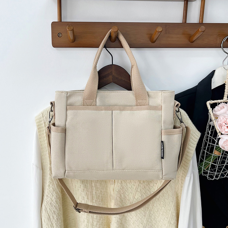 Geantă tote din pânză, cu stil urban minimalist, formă orizontală pătrată, închidere cu fermoar, buzunar pentru ID, trei curele de umăr și căptușeală poliester-bumbac.