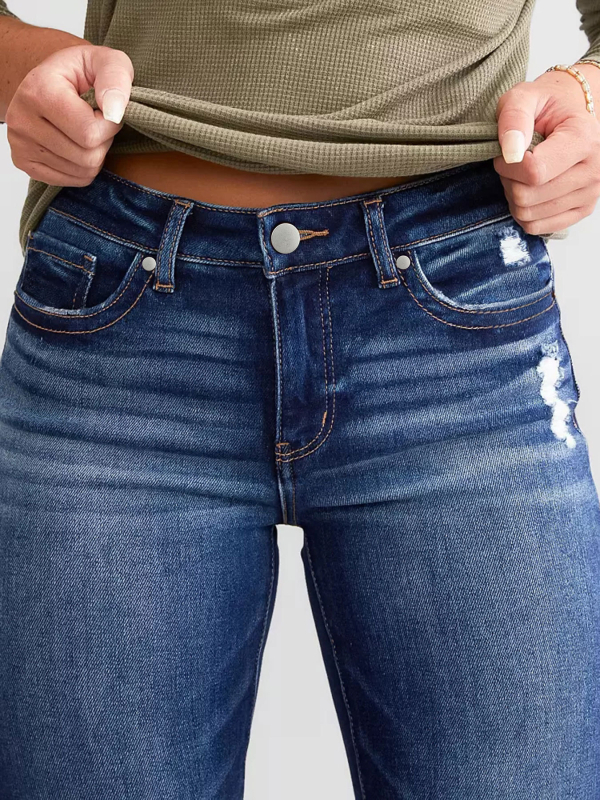 Moteriški džinsai iš džinsinio audinio, vidutinio juosmens, elastiniai, su įtrūkimais, šiek tiek platėjantys keliai, medvilnės-poliesterio mišinys (50–70% medvilnės, <30% poliesterio)