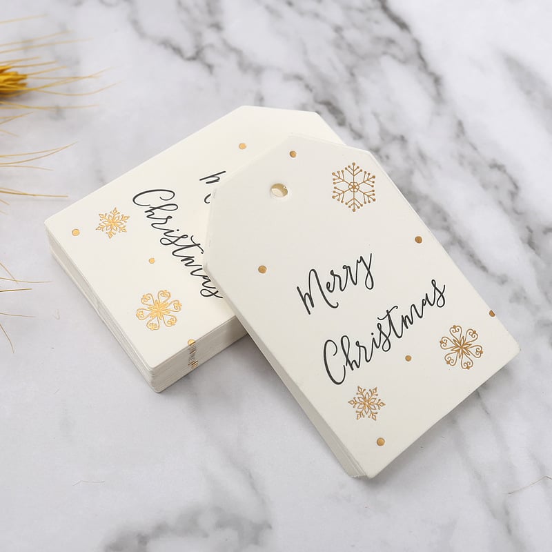 Kalėdinė dovanos etiketė su bronziniu įspaudu ant popierinės kortelės, su užrašu Merry Christmas ir snaigės dizainu