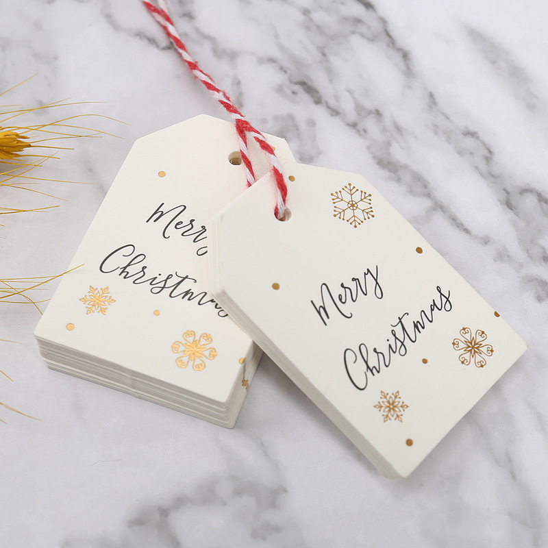 Kalėdinė dovanos etiketė su bronziniu įspaudu ant popierinės kortelės, su užrašu Merry Christmas ir snaigės dizainu