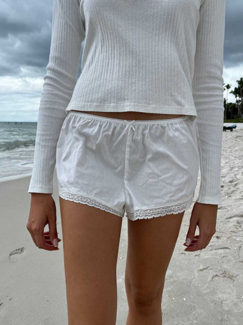 Moteriški nėrinių šortai su elastine žemąja juosmeniu, liekninanti siluetą, plačios kojos, poliesterio–medvilnės mišinys (90–95% poliesterio, <30% medvilnės).