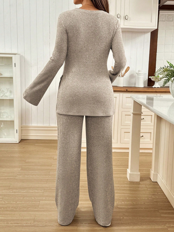 Grūtnieču divdaļīgs komplekts adītā materiāla: top ar zvanu piedurknēm un sānu griezumu, garas bikses ar regulējamu jostu.