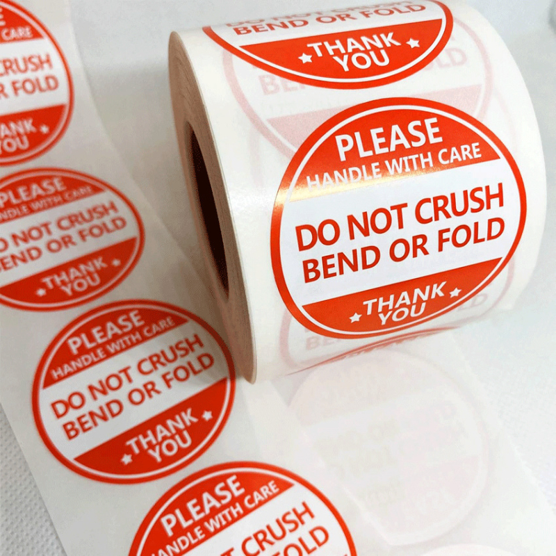 Sūtījuma brīdinājuma uzlīme – Ne saspiest, Ne salociet, Ne saliekt; Apaļa pašlīmējoša etiķete ar ūdens bāzes līmi, krāsu drukāšana, bez laminēšanas