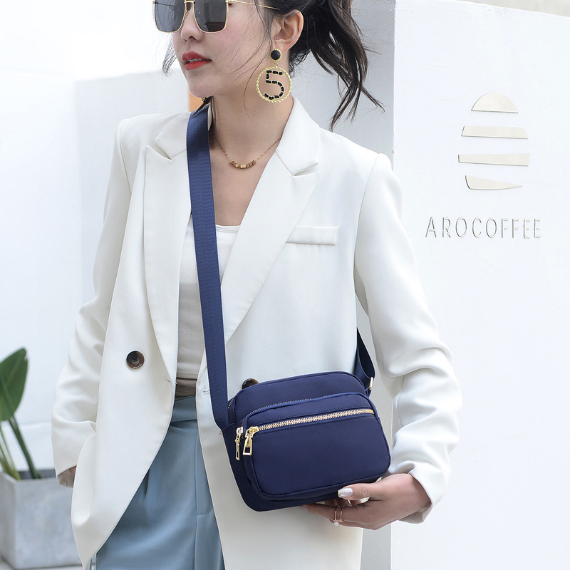 Női kompakt, négyzet alakú táska mindennapi használatra — városi egyszerű stílus, anyaga Oxford vászon, vízszintes négyzet alak, cipzáras nyitás, belső cipzáras zseb.