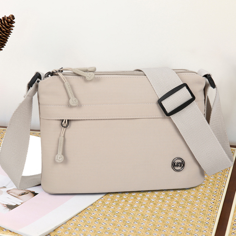 Nailona crossbody soma, pilsētas minimālisma stils, mazs kvadrāta formāts, rāvējslēdzēja atvērums, poliesteru odere, iekšējie kabati ar rāvējslēdzēju