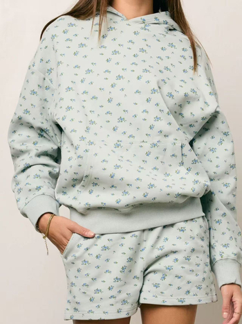 Moterų dviejų dalių komplektas rudens–žiemos sezonui su gėlių atspaudu kapucininiu megztiniu ir aukšto liemens šortais, euro-amerikietiškas gatvės stilius, 2025 ruduo