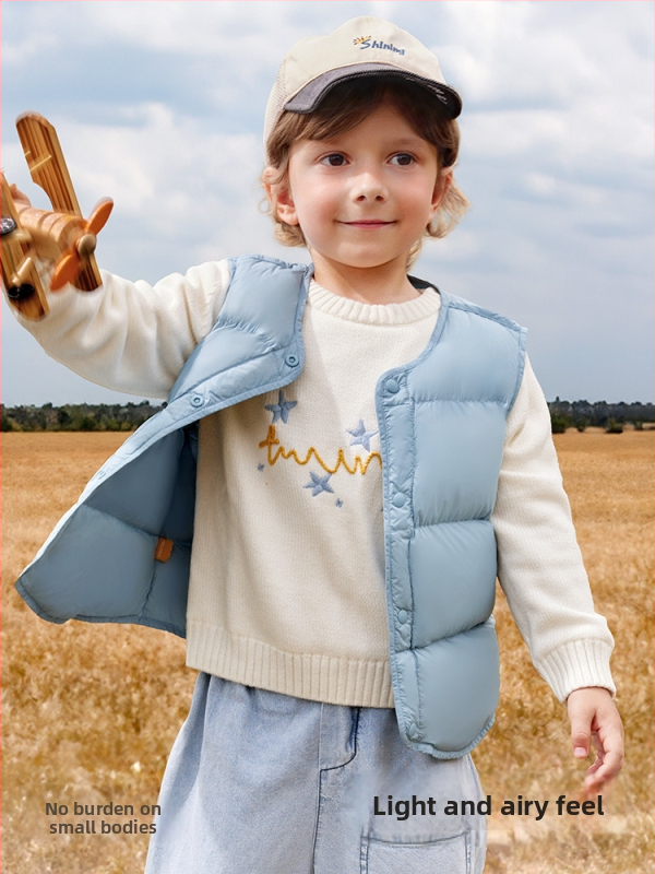 Bērnu pūka veste bez piedurknēm ziemai; pildījums: 90% balts pīļu pūks; ārējais materiāls un oderes no neilona; vidēja garuma, brīvs piegriezums; vecums 1–3 gadi.