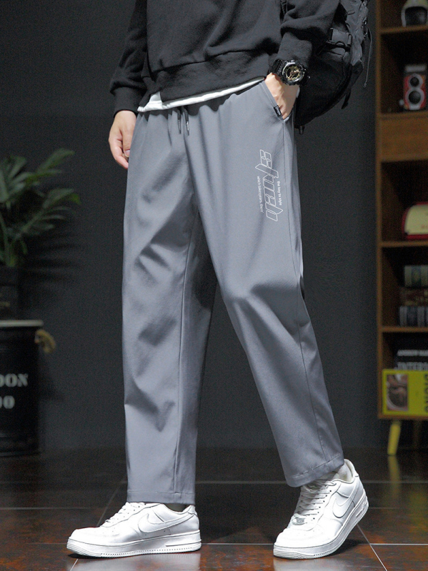 Pánske voľné športové nohavice, ľahký polyester s elastanom, stredný pás, šnúrka na stiahnutie, potlač s písmenami, leto