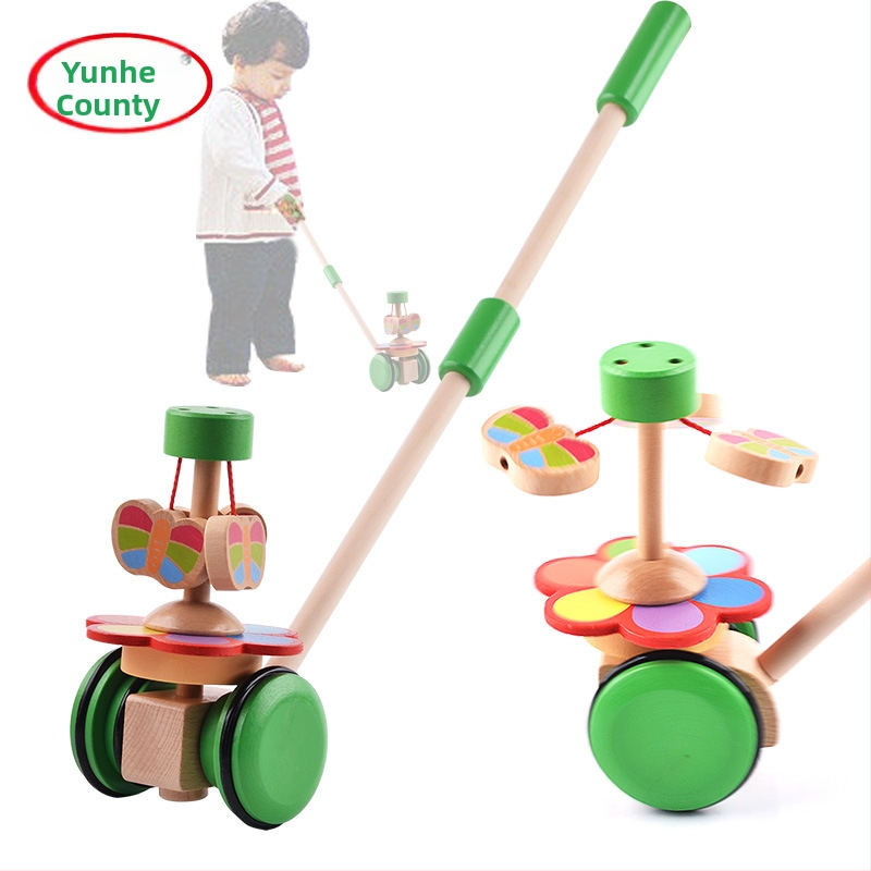 Koka gājienam paredzēta rotaļlieta zīdaiņiem 0–2 gadiem ar tauriņa rotējošu stieni; veicina jutību, vizuālo un kognitīvo attīstību un roku-acu koordināciju