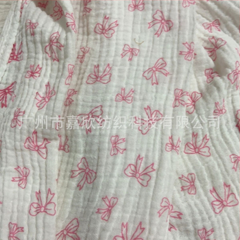 100% pamutból készült, dupla rétegű crepe muslin anyag, nyomtatott masni motívummal és tie-dye mintával; ideális babapizsamára, ágyneműre és otthoni viseletre