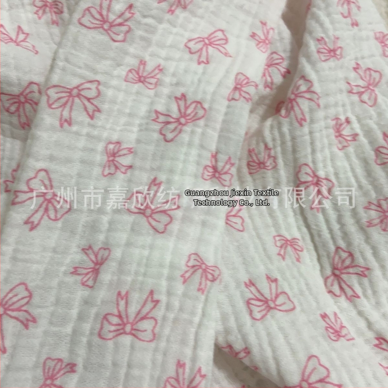 100% pamutból készült, dupla rétegű crepe muslin anyag, nyomtatott masni motívummal és tie-dye mintával; ideális babapizsamára, ágyneműre és otthoni viseletre