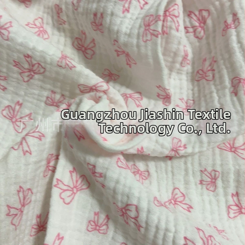 100% pamutból készült, dupla rétegű crepe muslin anyag, nyomtatott masni motívummal és tie-dye mintával; ideális babapizsamára, ágyneműre és otthoni viseletre