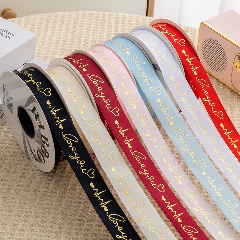 Satīna lente ar sirds motīvu un karstās drukas detaļām, piemērota dāvanu iesaiņošanai, ziedu kārtošanai un kūku dekorēšanai