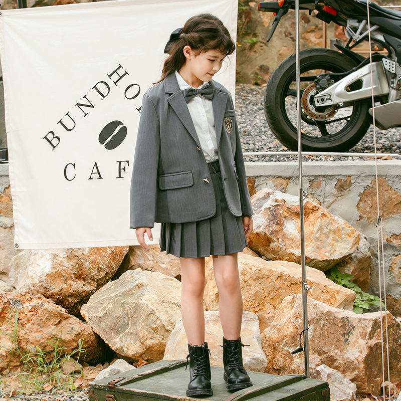 Meitenēm paredzēts īss jaka no kokvilnas maisījuma ar reveru, vienrindu pogu aizdari, vienkrāsains, garas piedurknes, piemērots vecumā no 8 gadiem (augstums >140 cm), skolas stils.