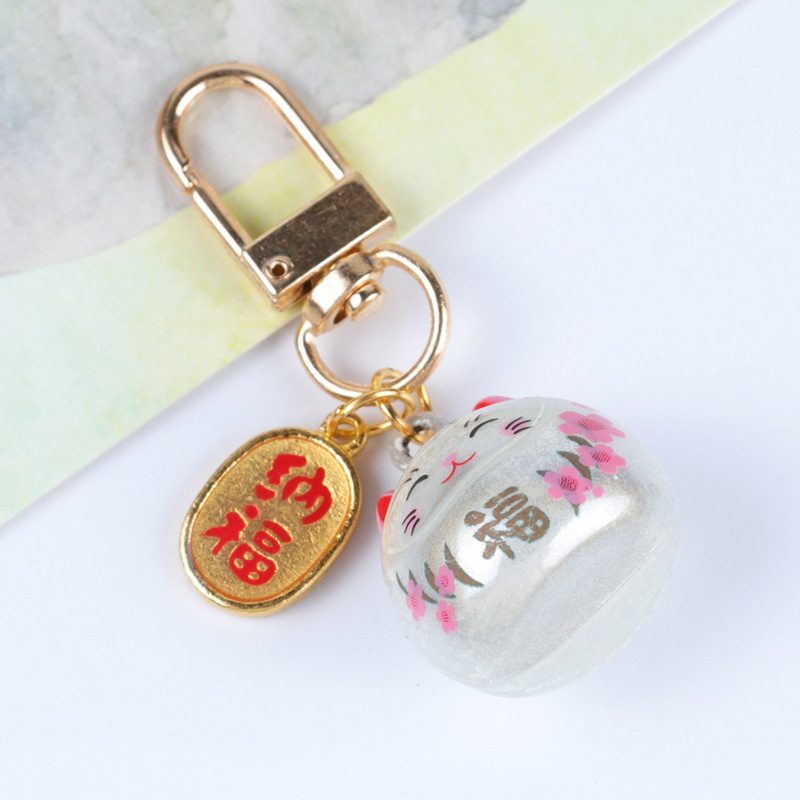 Metalo varpelio pakabukas su laimingos katės ir vyšnios žiedų motyvais