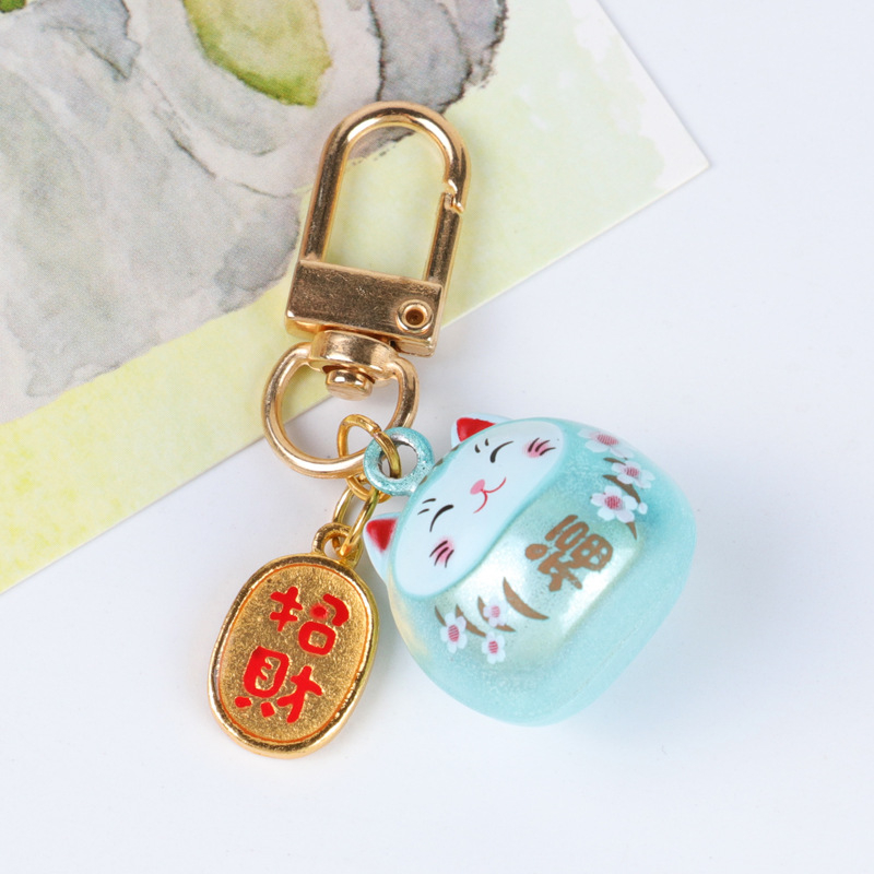 Metalo varpelio pakabukas su laimingos katės ir vyšnios žiedų motyvais