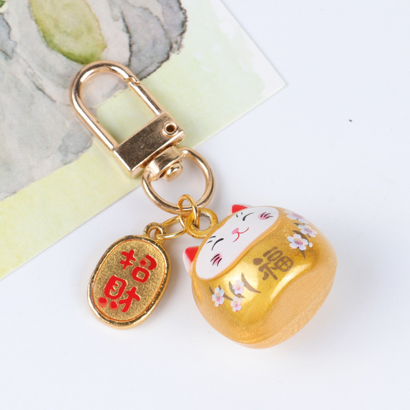 Metalo varpelio pakabukas su laimingos katės ir vyšnios žiedų motyvais