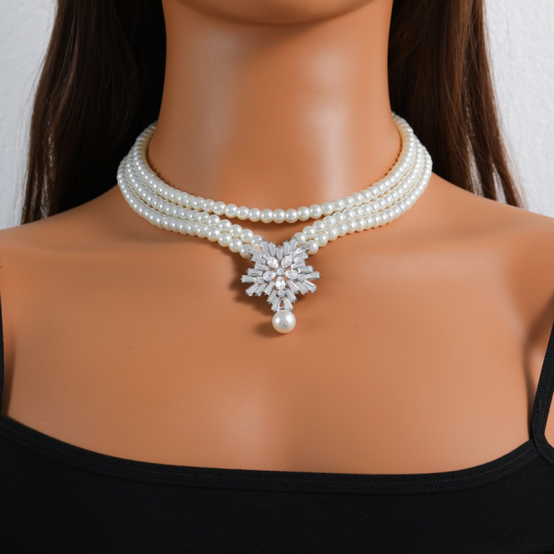 Dirbtinių perlų juvelyrinių komplektas: auskarai, karolė ir apyrankė; snaigių raštas; pakabuko medžiaga: lydinys; apdorojimo technologija: deimantas; medžiaga: dirbtinės perlai