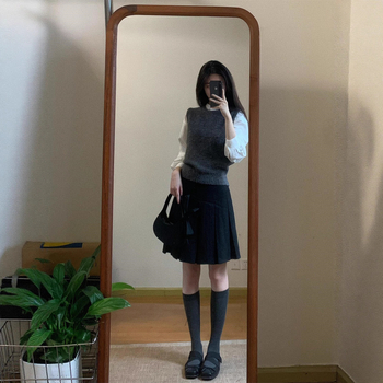 Trojdielny kostým: pletený vest, vrstvená košeľa a vysokopásová A-linijová plisovaná sukňa; jednofarebný vzor, stredná dĺžka sukne, retro štýl