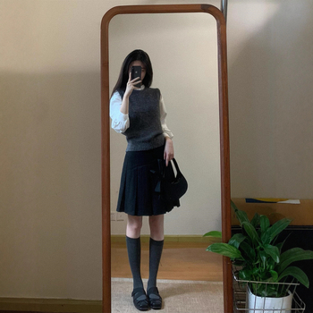 Trojdielny kostým: pletený vest, vrstvená košeľa a vysokopásová A-linijová plisovaná sukňa; jednofarebný vzor, stredná dĺžka sukne, retro štýl